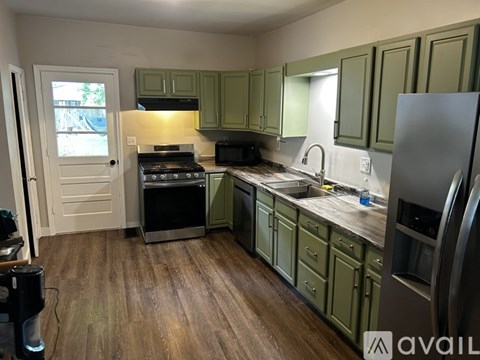 A kitchen with green cabinets and a wooden floor.