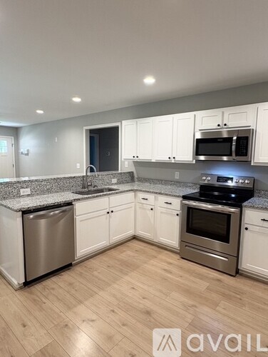 A kitchen with white cabinets and a wooden floor.