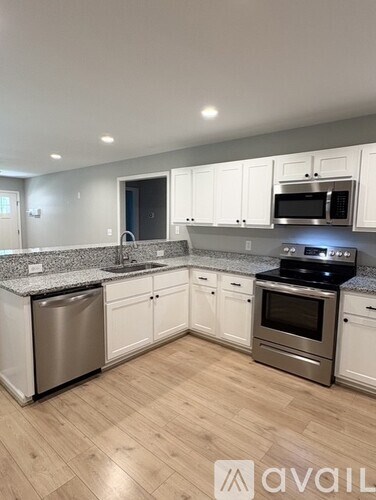 A kitchen with white cabinets and a wooden floor.