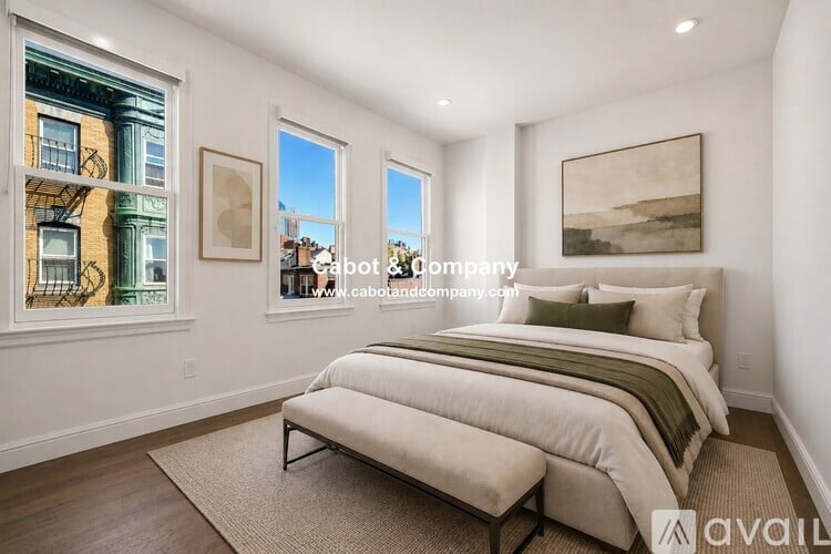 A bedroom with a large bed and a window overlooking a cityscape.