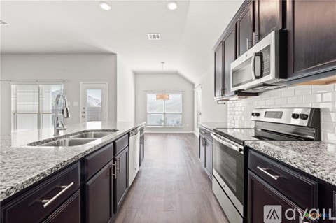 A modern kitchen with dark wood cabinets and stainless steel appliances.