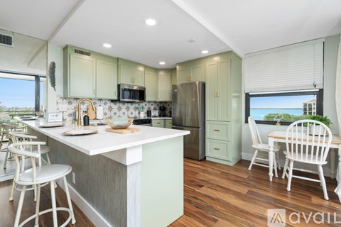 A kitchen with white chairs and a white table with a bowl on it.