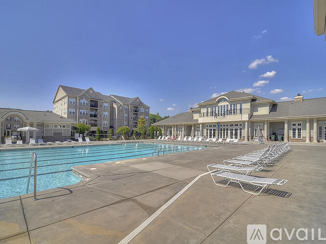 A large swimming pool with lounge chairs and a building in the background.
