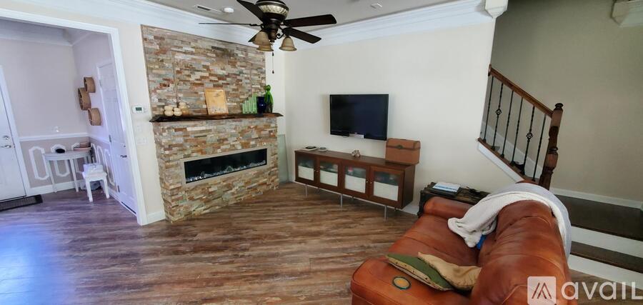 A living room with a stone fireplace and a television.