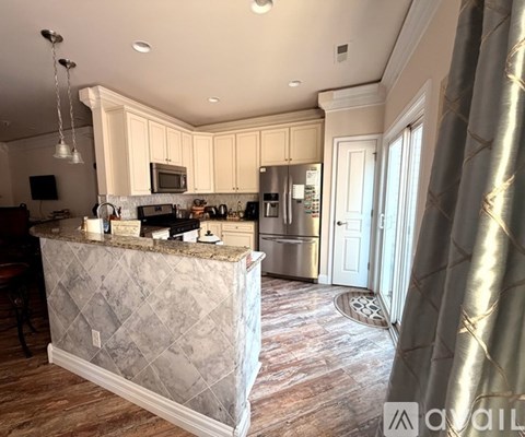 A kitchen with a marble island and stainless steel appliances.