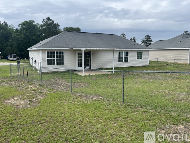 A white house with a grey roof and a fence in front of it.