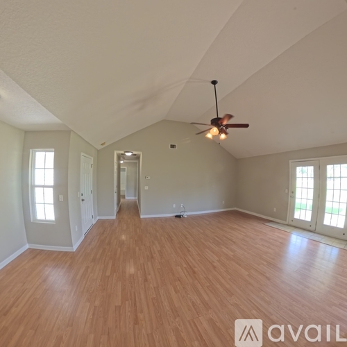 A spacious room with wooden flooring and a ceiling fan.