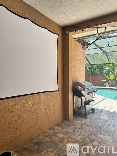 A whiteboard is on the wall in a room with a grill and pool in the background.