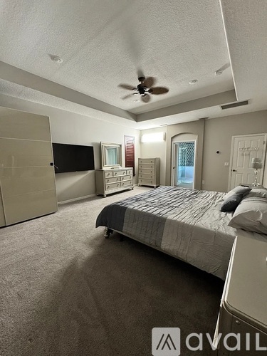 A bedroom with a bed, dresser, and a ceiling fan.