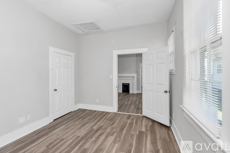 A spacious room with wooden flooring and white walls.