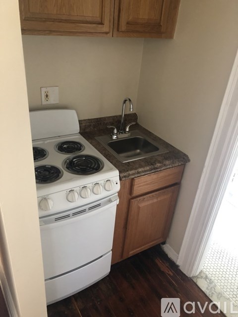 A white stove is in a kitchen with wooden cabinets.