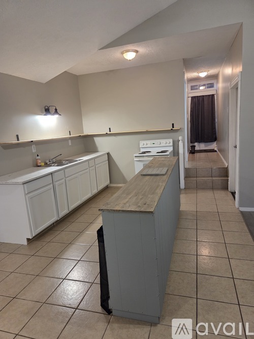 A kitchen with white cabinets and a wooden island.