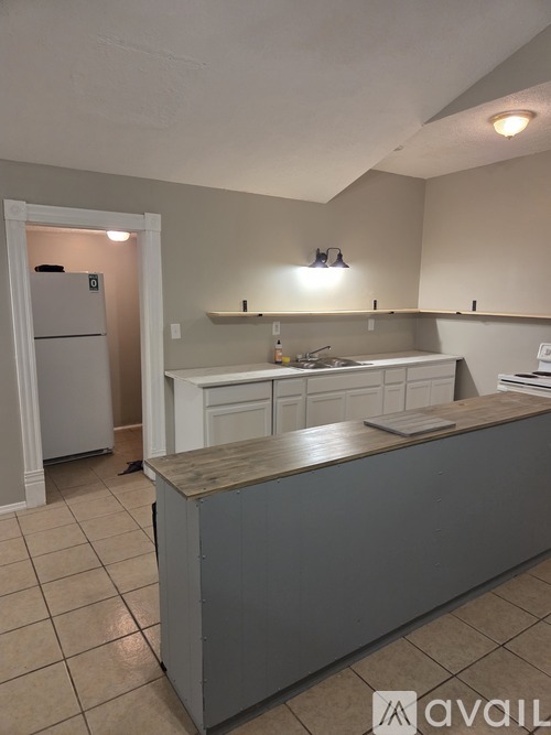 A kitchen with a refrigerator, sink, and cabinets.