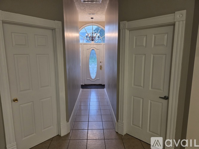 A hallway with white doors and a chandelier.