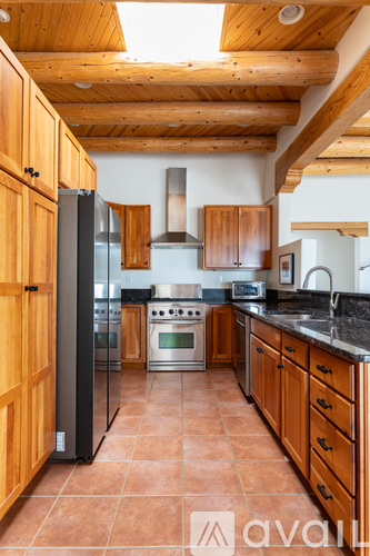 A kitchen with wooden cabinets and a black refrigerator.