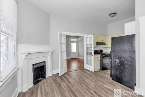 A kitchen with a fireplace and wooden floors.