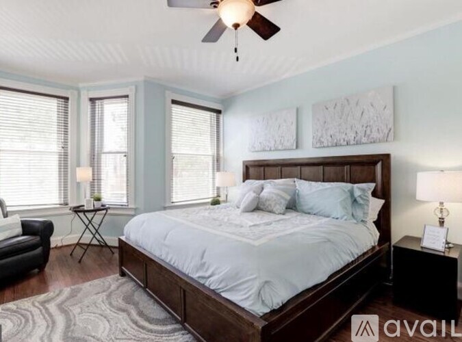 A bedroom with a large bed, a ceiling fan, and a rug on the floor.