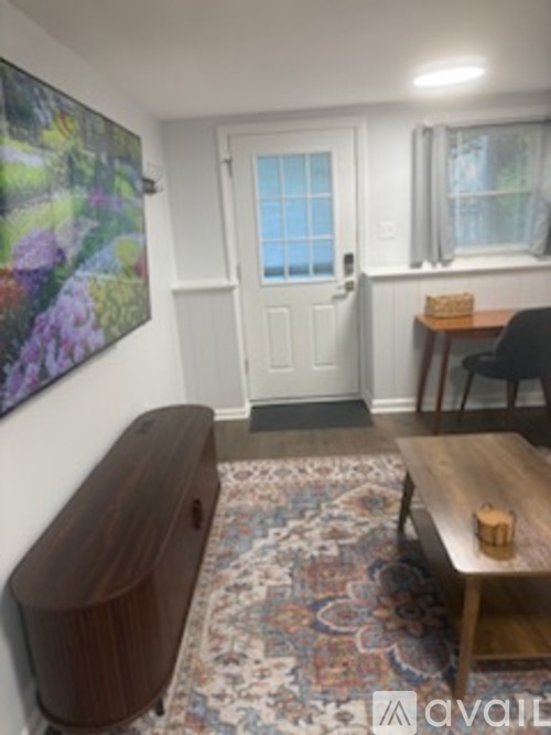 A room with a white door, a brown table, and a painting on the wall.