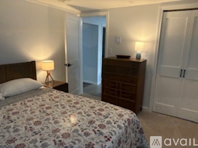 A bedroom with a floral bedspread and a wooden dresser.