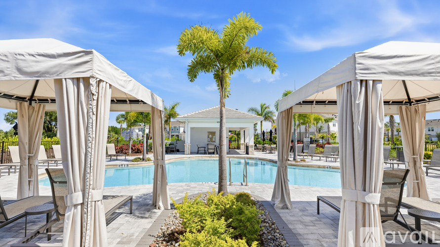 A pool area with a tree in the middle and two white canopies on either side.