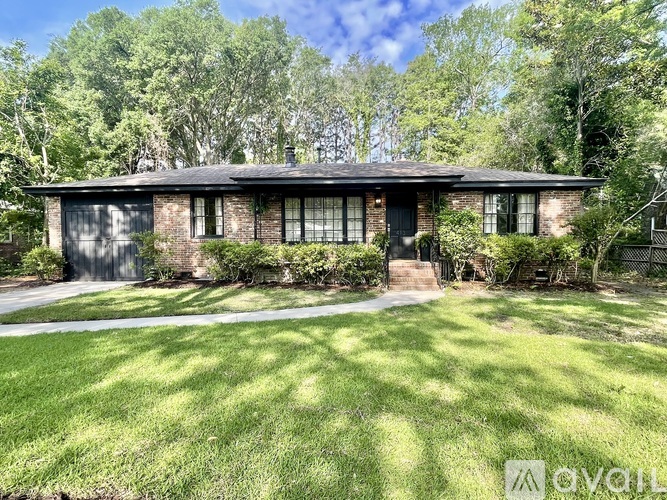 A house with a black roof and a green lawn in front.