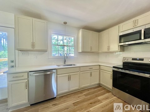A kitchen with white cabinets and a wooden floor.
