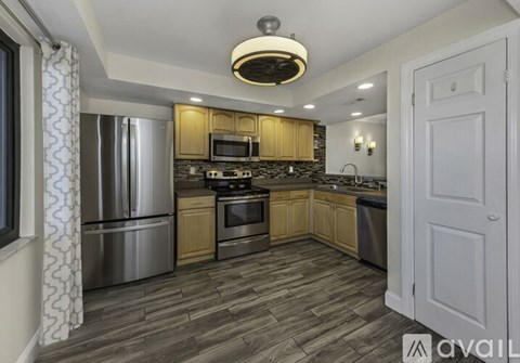 A kitchen with wooden cabinets and a stainless steel refrigerator.