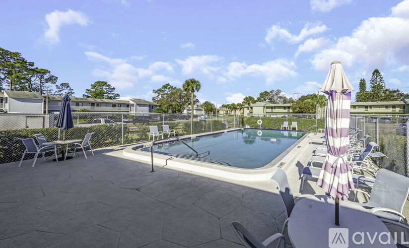 A pool area with chairs and a tall umbrella.