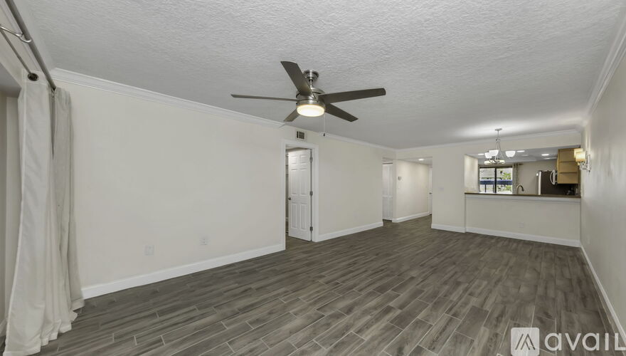 A spacious room with a ceiling fan and wooden flooring.