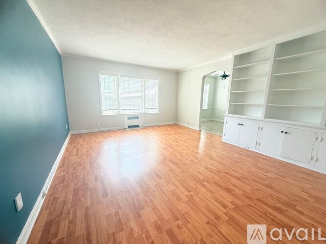 A room with wooden flooring and a window with blinds.