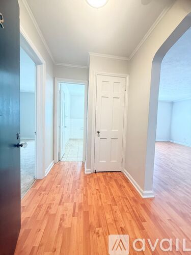 A hallway with wooden floors and white walls.