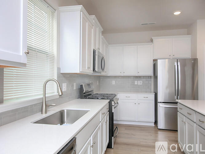 A kitchen with white cabinets and a stainless steel refrigerator.