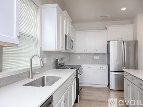 A kitchen with white cabinets and a stainless steel refrigerator.