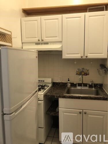 A kitchen with white cabinets and a white refrigerator.