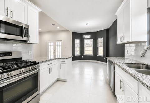 A modern kitchen with a black stove top oven and white cabinets.