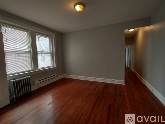 A room with wooden floors and a window with blinds.