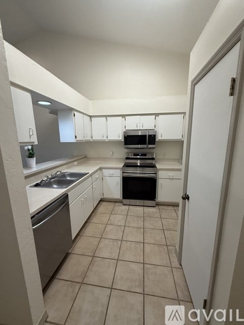 A kitchen with white cabinets and appliances, a sink, and a stove top oven.
