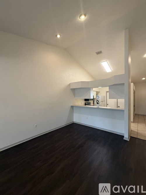 A room with white walls and dark wood flooring.