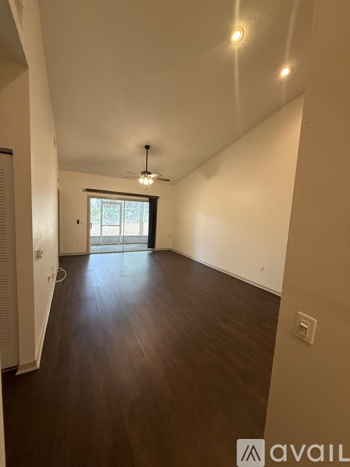 A spacious room with wooden floors and a ceiling fan.