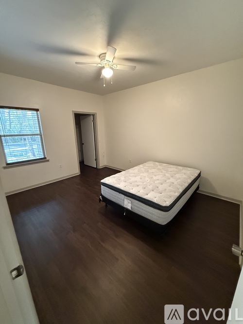 A bedroom with a bed, a ceiling fan, and a window.