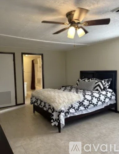 A bedroom with a bed and a ceiling fan.