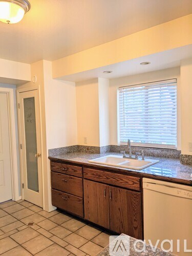 A kitchen with a sink and a window with blinds.