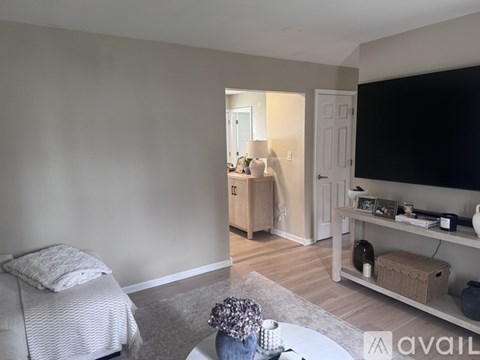 A living room with a grey sofa and a white bed.