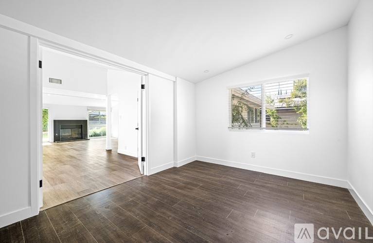 A spacious room with wooden flooring and a large window.
