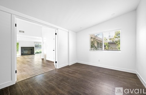 A spacious room with wooden flooring and a large window.