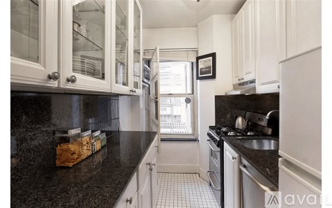 A kitchen with white cabinets and black countertops.