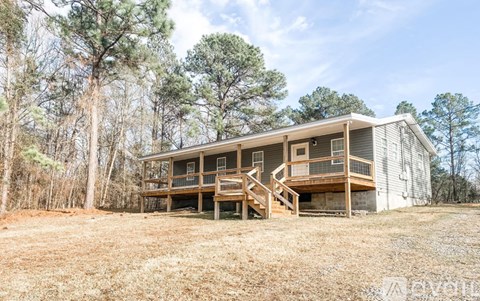 A two-story house with a balcony and a deck is surrounded by trees.