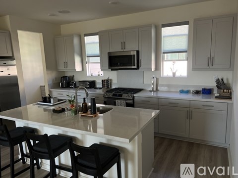 A kitchen with white cabinets and a large island with bar stools.