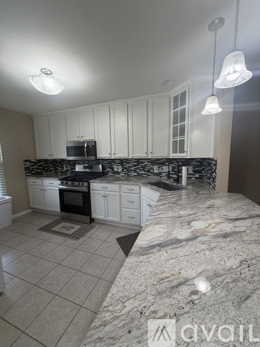 A kitchen with white cabinets and a marble countertop.