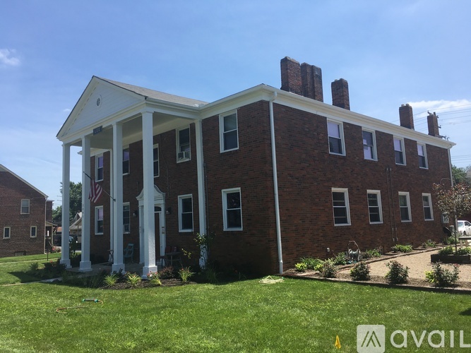 A red brick building with a white porch and a flag on the front.
